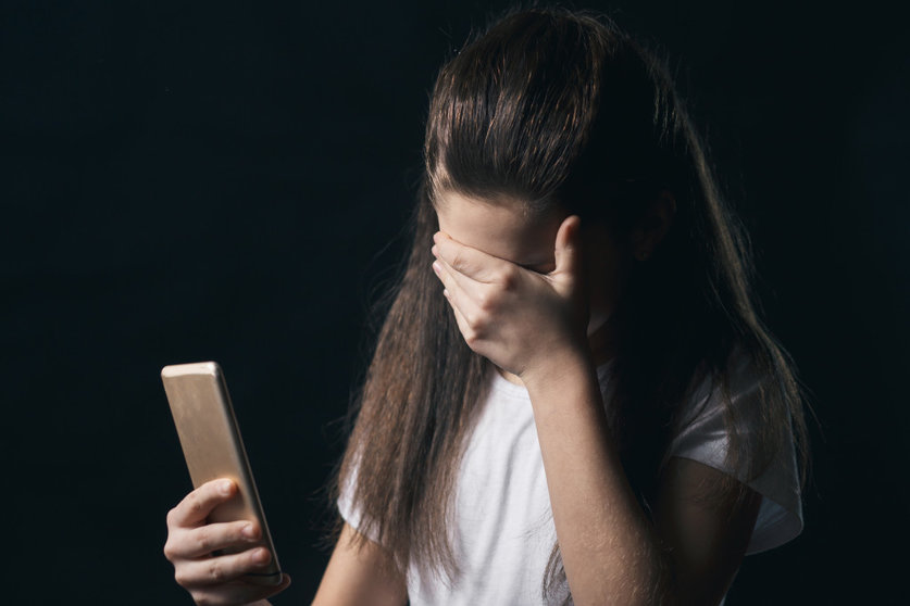 young sad vulnerable girl using mobile phone scared and desperate suffering online abuse cyberbullying being stalked and harassed in teenager cyber bullying concept