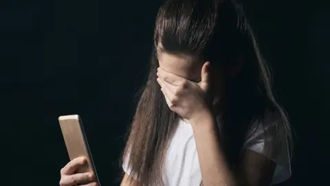 young sad vulnerable girl using mobile phone scared and desperate suffering online abuse cyberbullying being stalked and harassed in teenager cyber bullying concept